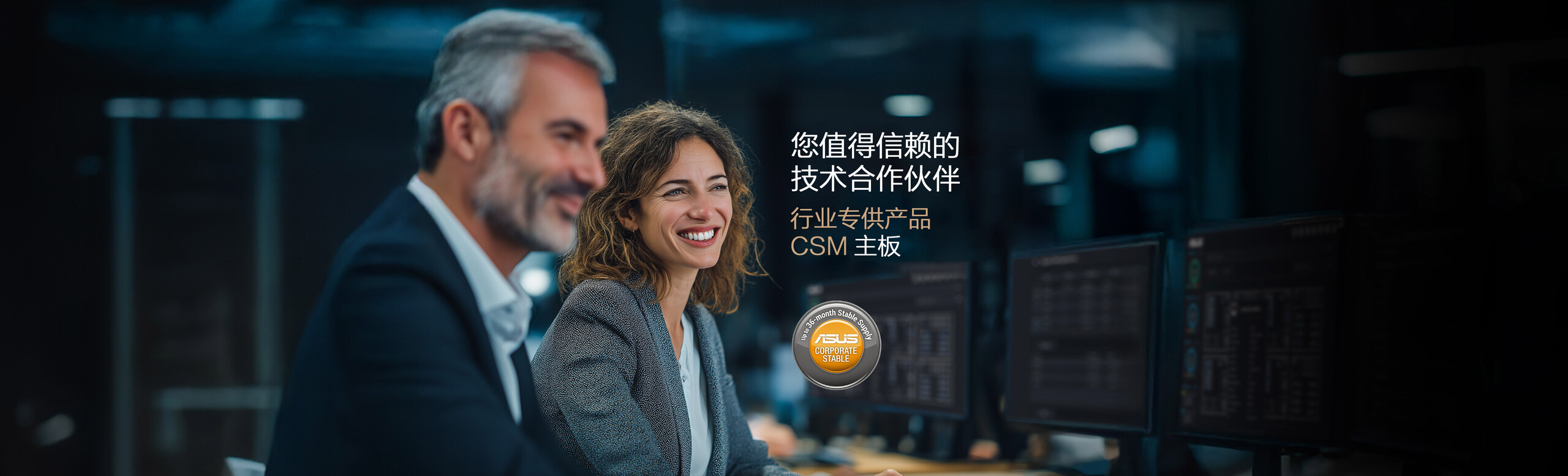 A man in a suit and a woman with wavy, light brown hair wearing a business jacket and white shirt are seated together at a desk in a modern office setting. Computer monitors are visible in the background, alongside promotional text for ASUS Corporate Stable Model (CSM) Motherboard: Your Trusted Technology Partner Program, and a circular badge stating 'Up to 36-month Stable Supply.'